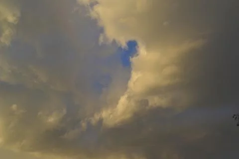 Yellow-blue gray clouds in the evening summer sky. Cumulus clouds. Stock Photos