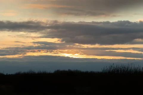 A yellow, blue sunset with thick clouds in the sky before a storm with a dark Stock Photos