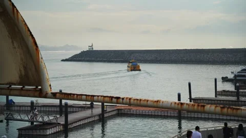 Yellow boat navigating away from a harbor pier into open water (August, 2026) Stock Footage 344139437