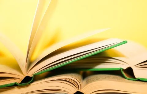 Yellow book stack, book pages turning, over a yellow background. Stock Photos