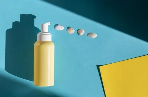 Yellow bottle with a dispenser and shells on a blue background. Foto stock