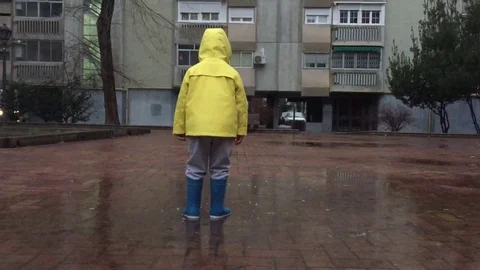 Yellow boy jumping in puddle in the rain Stock Footage 85349199