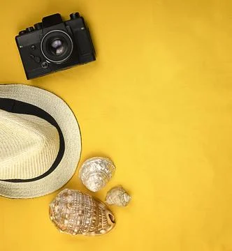 Yellow bright summer background with seashells, camera, straw hat Stock Photos