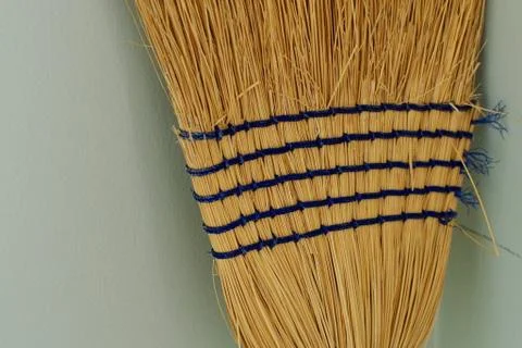 Yellow Broom Head With Blue Stripes Standing Upright Against A Wall Stock Photos