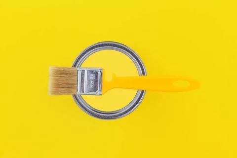 Yellow brush on an open can with yellow paint on a yellow background close... Stockfoto's