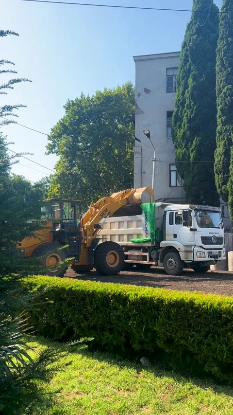 Yellow bucket loader pours soil into back of white dump truck Stock Footage 345601623