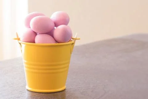 Yellow bucket with violet easter eggs Stock Photos