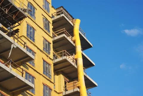 Yellow building in construction with downfall slide on blue sky Foto stock