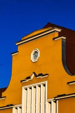 Yellow building facade with clock against blue sky Stock Photos