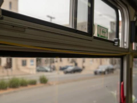 Yellow bus pull cord perched on top of window with city zooming Stock Photos