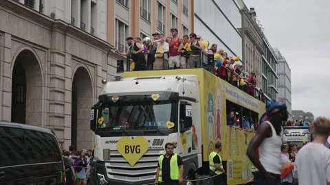 Yellow BVG public transit float with rainbow heart logo drives along city street Stock Footage 346240032