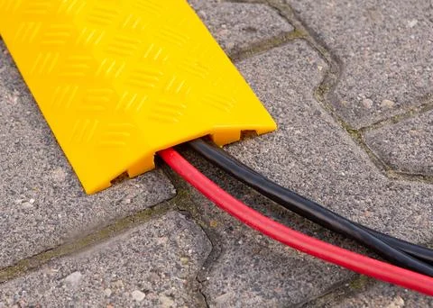 Yellow Cable Protector on Paved Surface Stock Photos