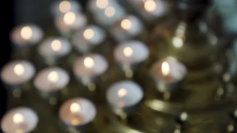 Yellow candle in front with many out of focus candles in background of church Stock Footage 221467946