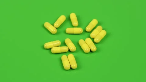 Yellow capsules on green background. Side view. Loop motion. Stock Footage 167057557