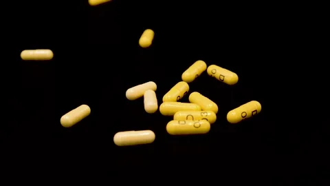 Yellow capsules pills are falling on a black surface Stock Footage 147550286