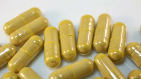 Yellow capsules on a white background move from right to left. Extreme close-up, Stock Footage 144643127