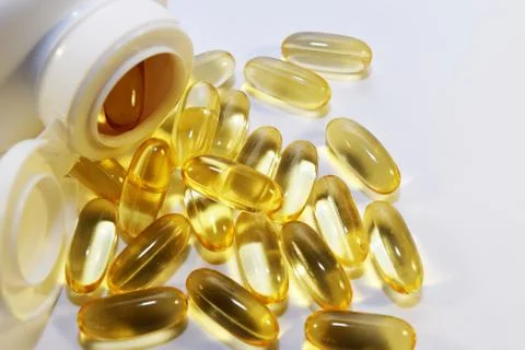 Yellow capsules on a white background. Stock Photos