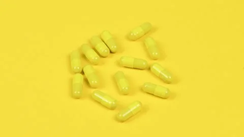 Yellow capsules on yellow background. Side view. Loop motion. Stock Footage 167056787