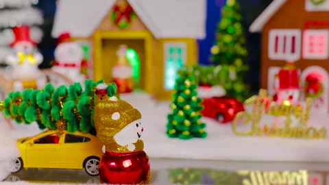A yellow car quickly drives up to a snowman against of Christmas village Stock Footage 344876010