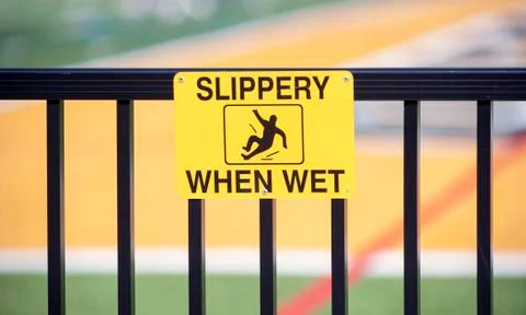 Yellow caution sign warns surface is "Slippery When Wet" Stock Photos
