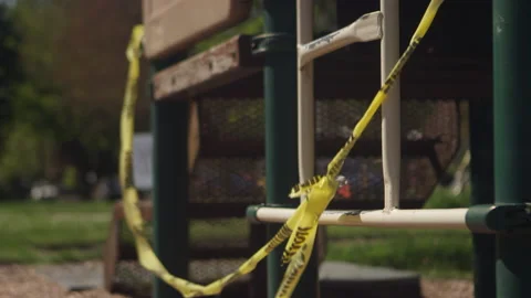 Yellow caution tape blowing in the wind at an empty playground Video stock 130386677