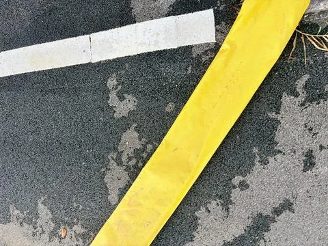 Yellow caution tape on a paved surface with a white line. Stock-Fotos