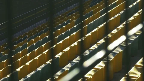Yellow chairs in an empty stadium behind a metal fence. Canceled match, game. 스톡 동영상 88428227