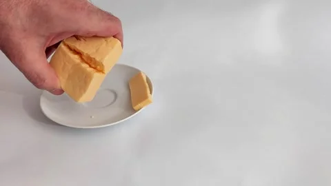 Yellow Cheese Block Cracked Open Above White Dish Video stock 320098159