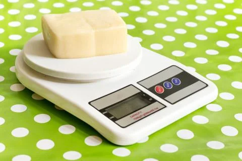 Yellow cheese on the kitchen digital scale Stock Photos