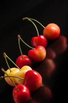 Yellow cherry on black reflective background Stock Photos