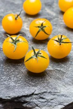 Yellow cherry tomatoes on stone background macro Stock Photos