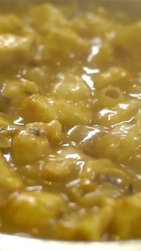 Yellow chicken curry bubbles and simmers in metal pot Video stock 334169655