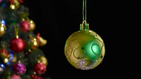 A yellow Christmas ball with a pattern rotates near a decorated Christmas tree Stock Footage 255119974