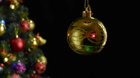 A yellow Christmas ball with a pattern rotates near a decorated Christmas tree Stock Footage 255119977