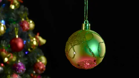 A yellow Christmas ball with a pattern rotates near a decorated Christmas tree Stock-Footage 255120109