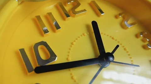 Yellow clock with black arrows running in a circle, close-up. Video stock 104402789
