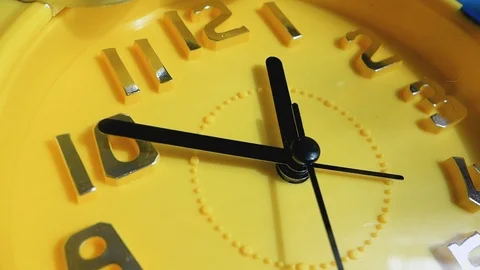 Yellow clock with black arrows running in a circle, close-up. Stock Footage 104403691