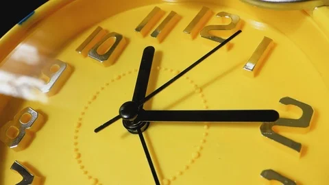 Yellow clock with black arrows running in a circle, close-up. Video stock 104404934