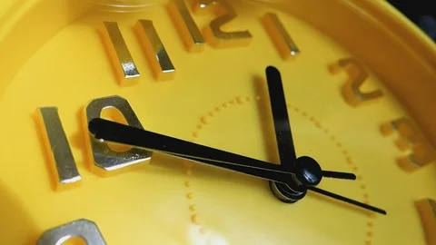 Yellow clock with black arrows running in a circle, close-up. Video stock 104416177