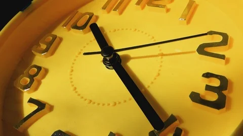Yellow clock with black arrows running in a circle, close-up. Video stock 104435166