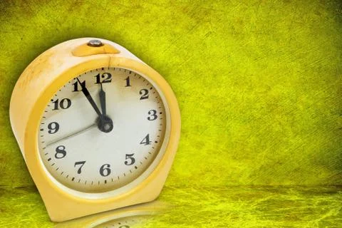 Yellow clock on green background Stock Photos