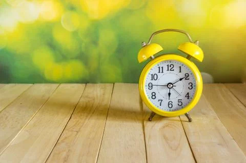 Yellow clock on wood table Stock Photos