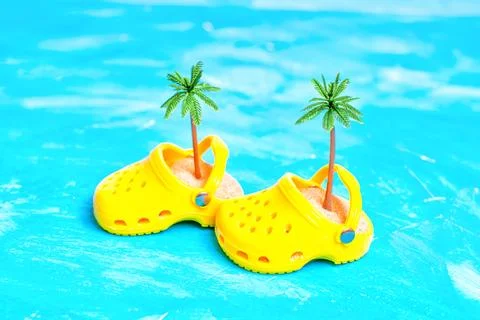 Yellow Clogs with Sand and Palm Trees on Blue Foto stock
