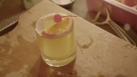 Yellow Cocktail with Orange and Cherry Garnish Served on Bar Counter in Beijing Stock Footage 345754645