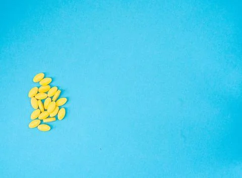 Yellow colored pills on a blue surface Stock Photos