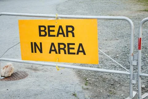 Yellow colored warning sign Bear In Area informing about wildlife activity in Stock Photos