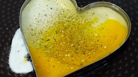 Yellow colorful scrambled eggs in the shape of a heart on frying pan. Stock Footage 89034953