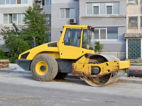 Yellow combination asphalt compactor at the site of road construction Stock Photos