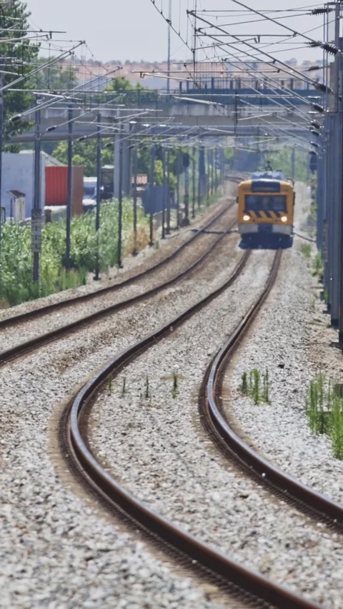 Yellow commuter train arriving on a winding railway track Stock Footage 329472528