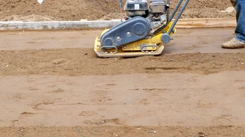 Yellow compactor operated by working man on dirt before concrete is poured. Stock Footage 156633660